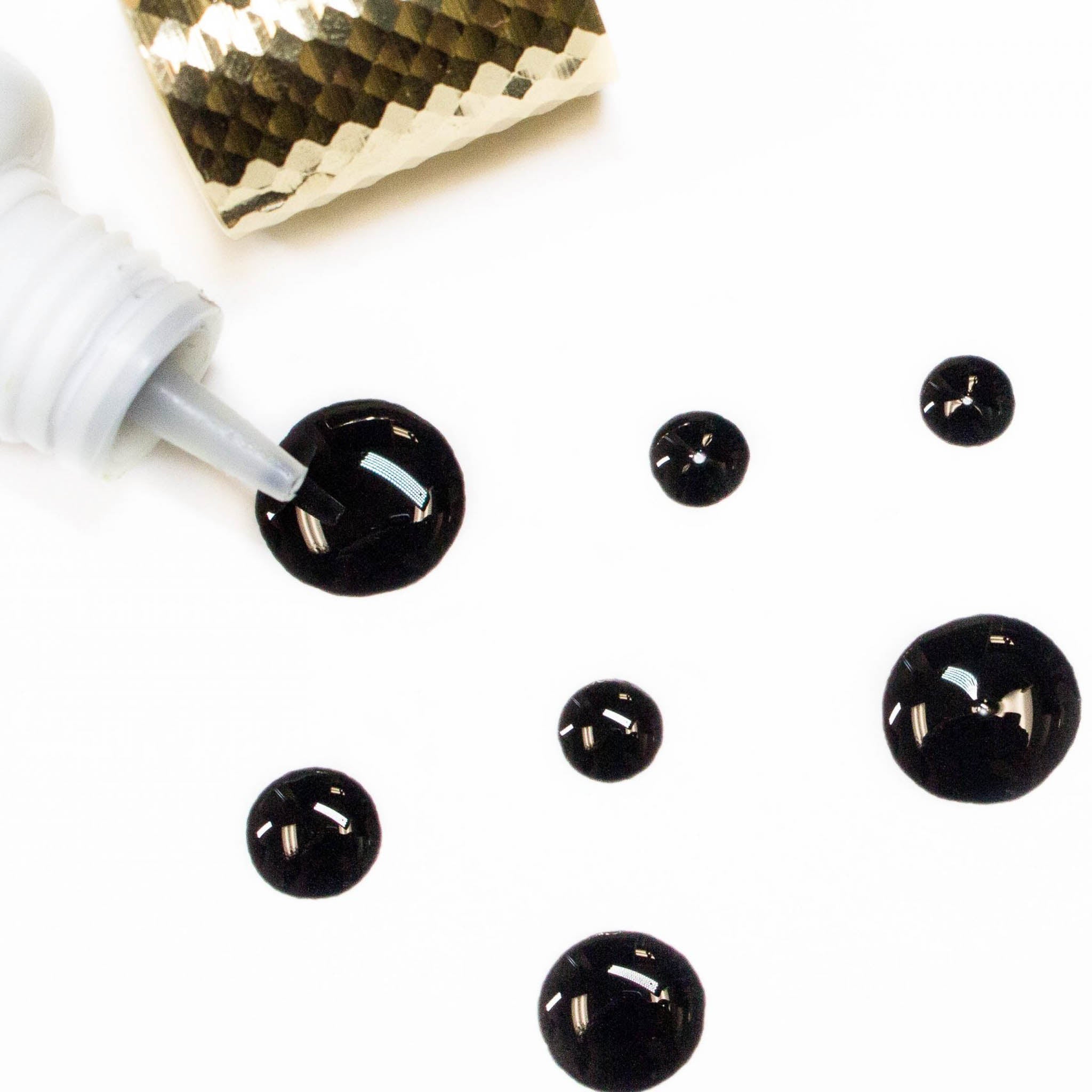Colle d'extensions de cils noir Buddha -  solidification instantanée, application rapide (pour techs avancées), séchage en 1-2 secondes, faible viscosité, peu de vapeurs, image avec 7 gouttes de colle noire pour montrer la viscosité | Buddha black eyelash extension glue - Professional-grade black adhesive, instant solidification, fast application (for advanced techs), 1-2 second drying time, low viscosity, minimal fumes, image featuring 7 drops of black glue to showcase viscosity